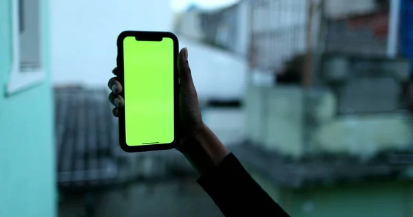 Female black hand holding cellphone with green screen mock-up