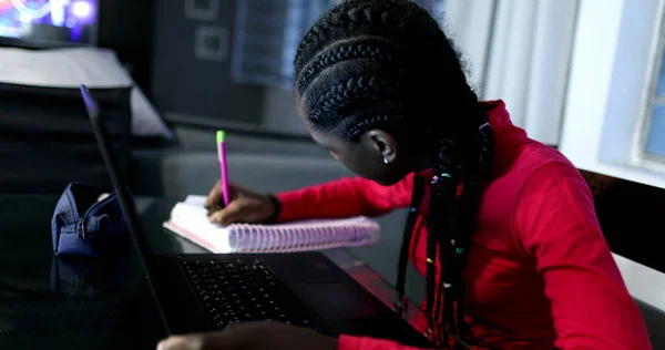 Candid black girl studying at night in front of laptop computer