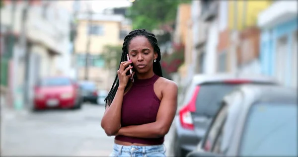 Candid African woman speaking on phone outside. Casual black woman talking on cellphone in street