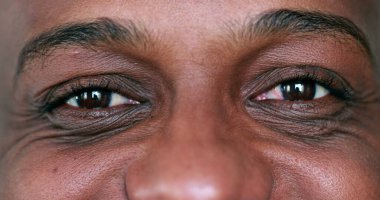 Ekstrem yüz, siyah Afrikalı adamın yana bakan makro gözleri.