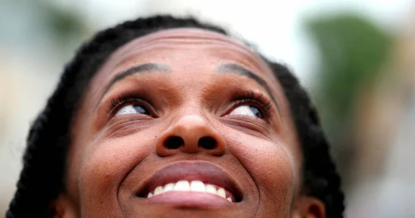 Black African woman close-up face looking at sky feeling happy