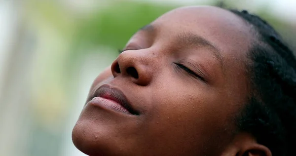 Black African girl closing eyes outside