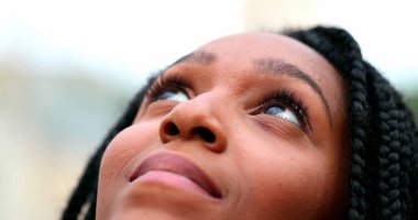 Afrikalı kadın gökyüzüne bakıyor özgürlüğü ve mutluluğu hissediyor, siyah kız yakından bakıyor.