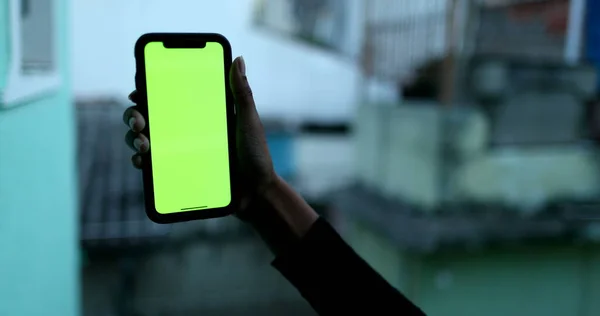 African hands holding smartphone device showing media, green screen mock-up