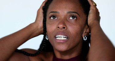 Desperate African woman screaming in HORROR to news, close-up face YELLING and desperation