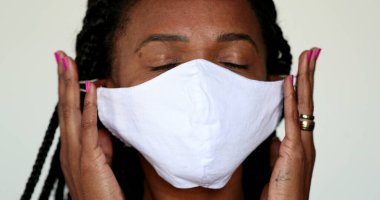 Afrikalı bir kadın, salgın konseptinin sonu için Coperid-19 maskesini çıkarıyor.