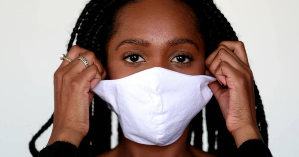 African teen girl removing face mask in relief. Person takes off mask