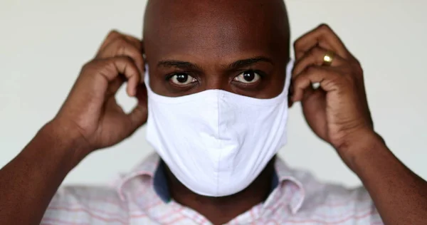 African man wearing covid-19 face mask, portrait black guy putting face mask