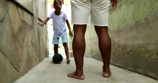 Father and son playing football together. African parent bonding with child. Playing sport