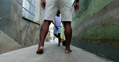 African father and child boy playing soccer together at home alley