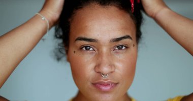 Siyah Afrikalı kadın kameraya bakarak saçlarını düzeltiyor.