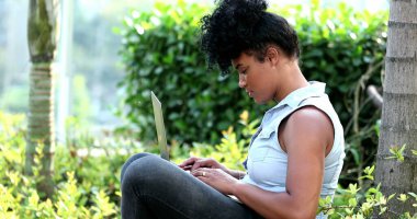 Dışarıda dizüstü bilgisayar kullanan Afrikalı kadın