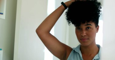 Afrikalı Amerikalı kadın aynanın önünde saçlarını düzeltiyor.