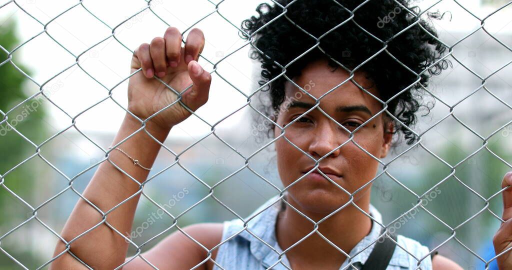African woman leaning to metal fence looking at camera