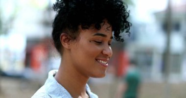 Açık havada gülümseyen mutlu ve çeşitli bir kadın.