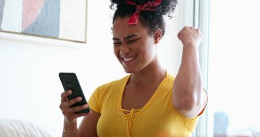Mutlu siyah kız başarısını evden gelen akıllı telefondan yumruk okuyarak kutluyor.