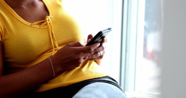 Evdeki koltukta oturan gizli zenci kız cep telefonu kullanıyor.