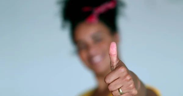 Happy African woman gives thumb up to camera in positive gesture