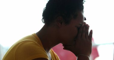 Üzgün genç siyah kadın elleriyle yüzünü kapatıyor.