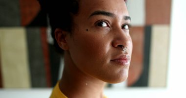 Melez ırk genç siyahi kadın, kameraya bakıyor.