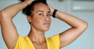 Saç ayarlayan melez bir genç kadın. Siyah Afrikalı Amerikalı kız kameraya bakıyor.