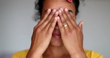 Düşünceli siyah kadın elleriyle yüzünü ovuşturuyor.