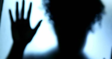 Depresyon konsepti, camın arkasında kapana kısılmış kadın gölgesi.