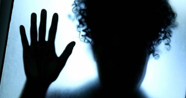 Depresyon konsepti, camın arkasında kapana kısılmış kadın gölgesi.