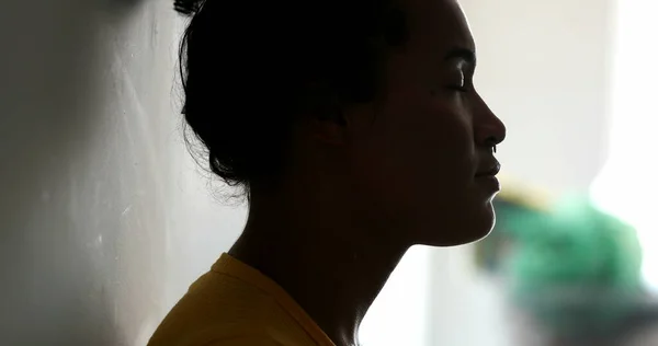 Spiritual black woman hands on chest leaning on wall in meditation