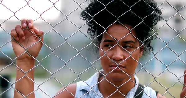 Pensive sad black woman holding metal fence