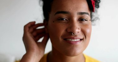 Genç siyah kadın kameraya gülümsüyor.