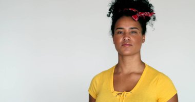 Beyaz arka planda duran, sarı elbiseli genç siyahi kadın.