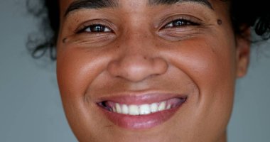 Genç siyah kadın makro yakın çekim yüzü kameraya bakıp gülümsüyor.