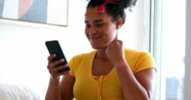 Genç siyahi kadın ekranda mesaj okuyor ve başarıyı kutluyor.