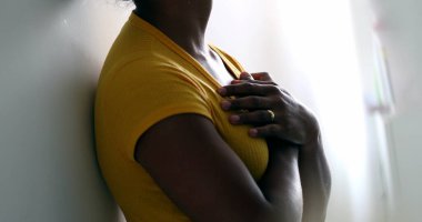 Ruhani siyah kadın ellerini göğsüne koyup meditasyonda duvara yaslanıyor.