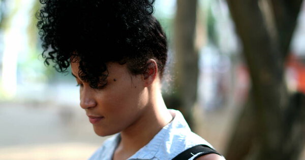 Young black African woman standing outdoors thinking