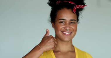 Genç melez kadın kameraya baş parmağını uzatıyor.