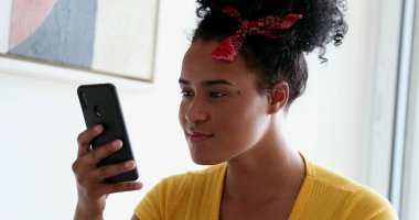 Genç mutlu melez kadın telefonda yumruk okuyarak kutlama yapıyor.