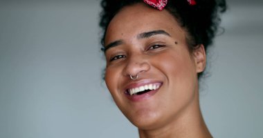 Genç etnik çeşitlilikte bir kadın kameraya gülümseyerek poz veriyor.