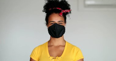 Karışık ırktan genç bir kadın virüs salgınına karşı maske takıyor.