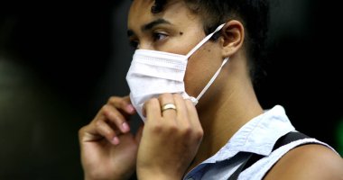 Metroya binerken yüz maskesi takan melez bir kadın.