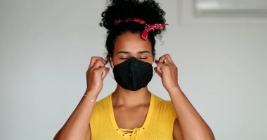 Happy young black woman taking off pandemic mask feeling relief