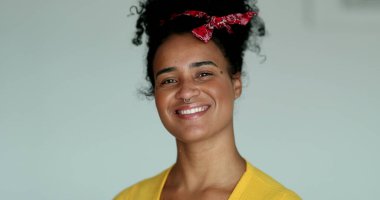 Genç milenyum melez kadın kameraya gülümseyen yüz maskesini çıkarıyor.