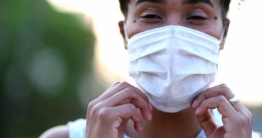 Young African black woman putting covid-19 face mask outside