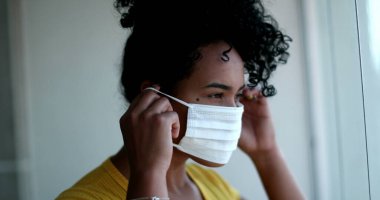 Young African American woman putting face mask