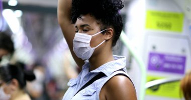 Metro tırabzanı tutan bir kadın. Kovid-19 yüz maskesi takıyor.