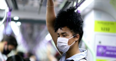 Metro tırabzanı tutan bir kadın. Kovid-19 yüz maskesi takıyor.