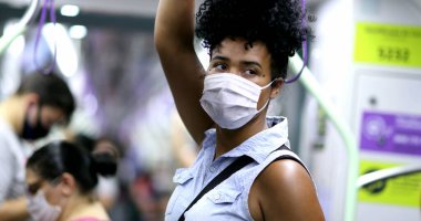 Metro tırabzanı tutan bir kadın. Kovid-19 yüz maskesi takıyor.