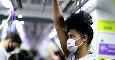 Metro tırabzanı tutan bir kadın. Kovid-19 yüz maskesi takıyor.