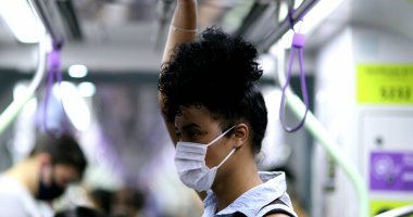 Metro tırabzanı tutan bir kadın. Kovid-19 yüz maskesi takıyor.